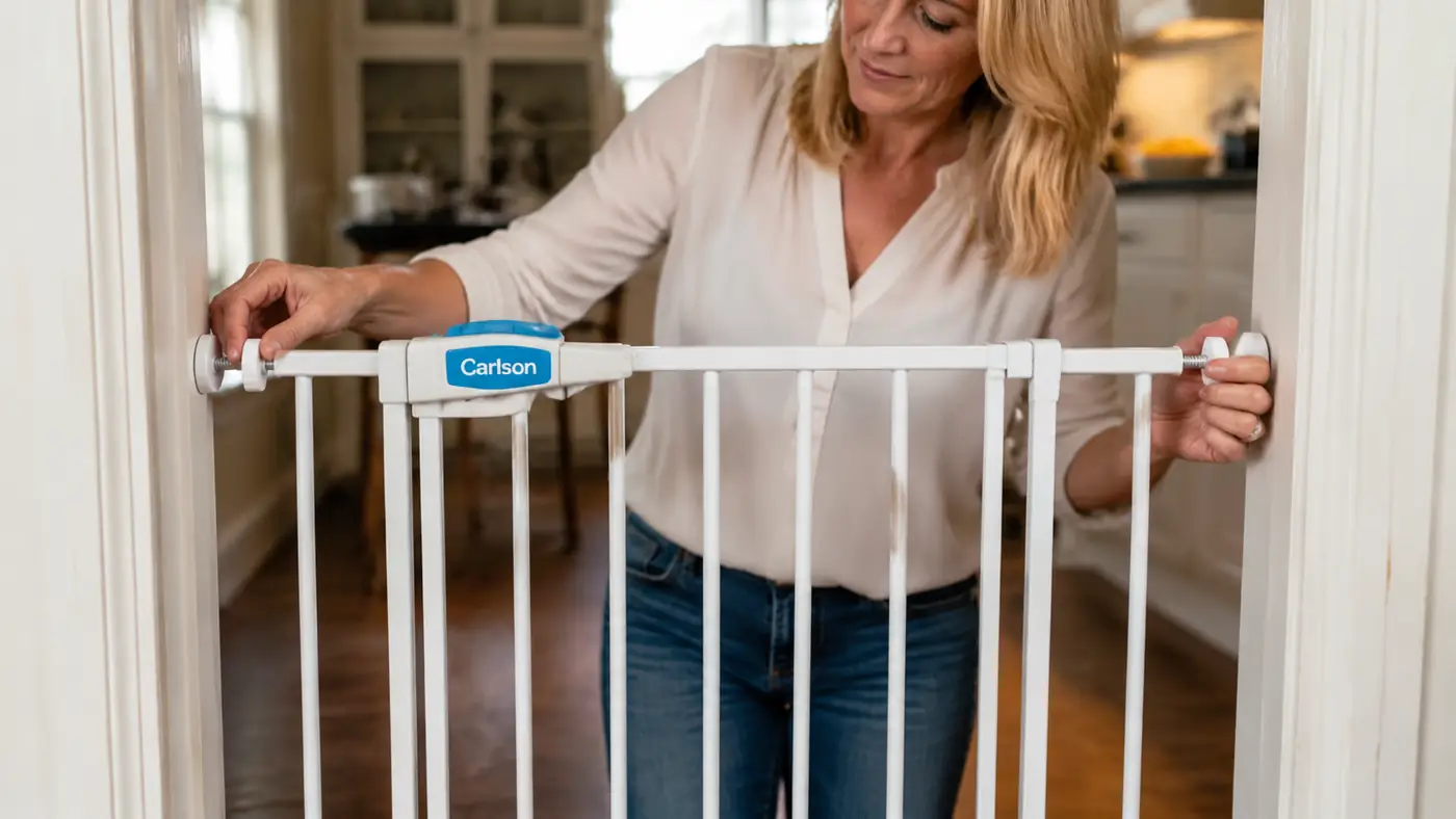 Hand adjusting the pressure-mount knobs on a walk-through pet gate installed in a doorway